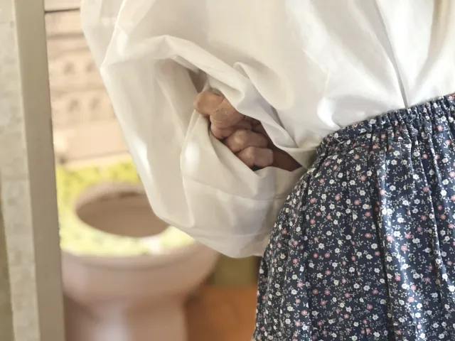 お腹が痛くて抑えている女性